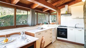 A kitchen with a stove, sink, and window overlooking greenery. - 2 bedroom amazing home in Perdifumo SA (Perdifumo SA)