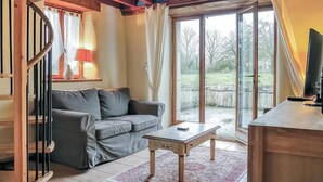 A cozy living room with a grey sofa, a small table, and a TV on a wooden stand. - 2 bedroom awesome home in Brucheville (Brucheville)