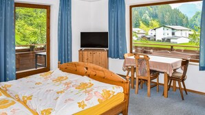 Un dormitorio con cama, televisión, mesa de comedor y sillas.