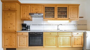 Una cocina con armarios de madera, lavavajillas, horno y cafetera.