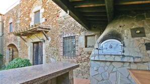 A stone building with a rustic outdoor kitchen area, including a stone oven and a countertop. - Gorgeous home in Calonge (Calonge)