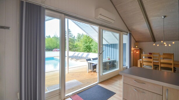 Une cuisine moderne dotée d’une grande porte-fenêtre coulissante donnant accès à un espace piscine.