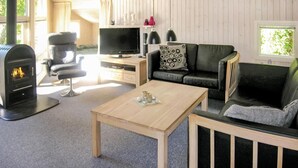 Ett mysigt vardagsrum med en öppen spis, en tv, en soffa och ett soffbord.