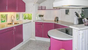 Ett kompakt kök med rosa skåp, en inbyggd diskmaskin och en rund köksö med en diskho.
