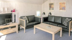 Ett vardagsrum med en TV, två soffor, ett soffbord och konstverk på väggarna.