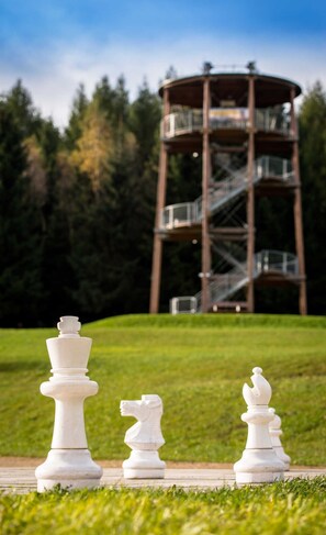 Three chess pieces on a paved path with a tower in the background. - Waldfrieden - maple avenue (Altenberg)
