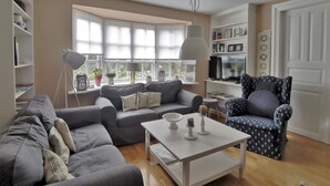 A living room with a sofa, armchair, coffee table, and a TV.