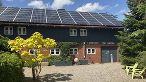 A building with solar panels on the roof, a brick facade, and a sign reading 'Landhaus Westerweg.'