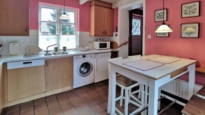 A kitchen with a washing machine, a microwave, and wooden cabinets.