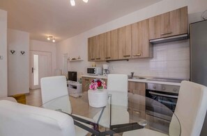 A modern kitchen with wooden cabinets, a microwave, a coffee maker, and a glass dining table.