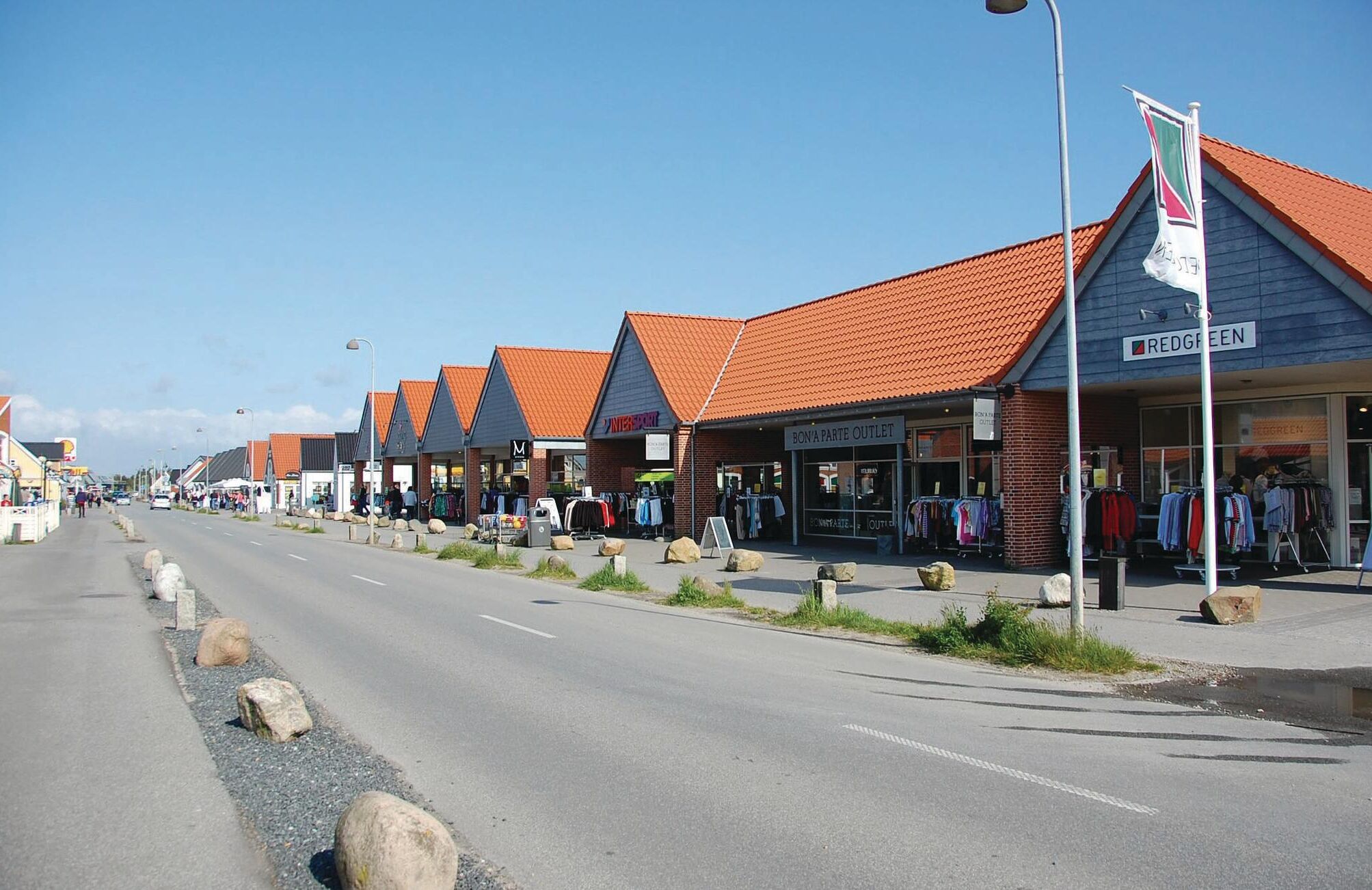 Une rangée de boutiques aux toits orange, sous un ciel dégagé.
