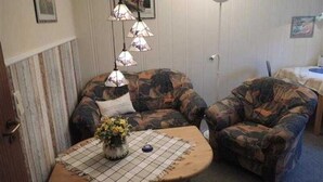 A room with a sofa, a table with a vase, and hanging lamps.