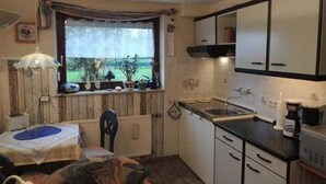A compact kitchen with a window, a table with a chair, and cabinets.