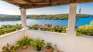 Ein Balkon mit Topfpflanzen, Blick auf einen See und eine Angelzierde.