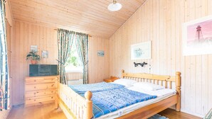 A wooden-paneled bedroom with a bed, dresser, and a window with curtains.