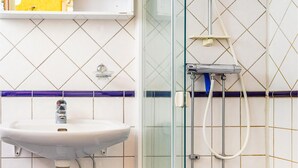 A bathroom with a sink, a shower, and a glass door.