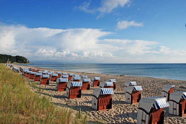 A beach with rows of wooden beach huts with striped awnings.