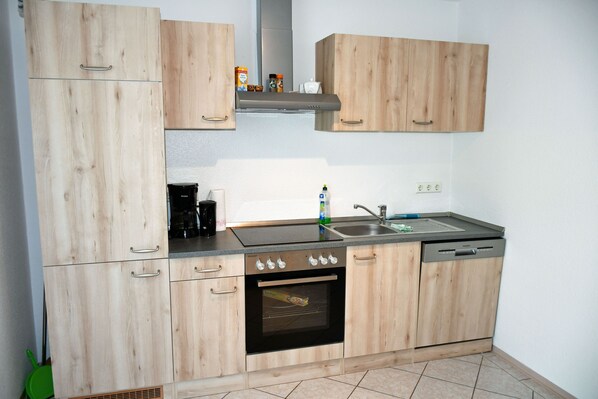 A kitchen with wooden cabinets, a stove, a sink, and a dishwasher. - 01 Holiday apartment Sehlen with terrace (6 beds) - Ferienappartements auf (Sehlen)