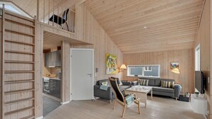 A cozy cabin interior with a loft bedroom, a dining area, and a living room.