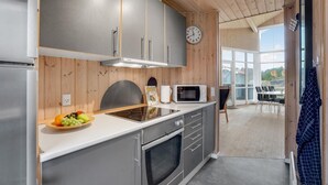 A modern kitchen with grey cabinets, a microwave, a stove, and a fruit bowl.