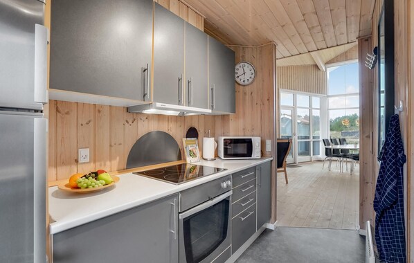 Een moderne keuken met grijze kastjes, een magnetron, een fornuis en een fruitschaal.