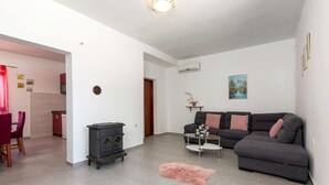 Een woonkamer met een bank, een salontafel, een vloerkleed en een keuken met een fornuis.