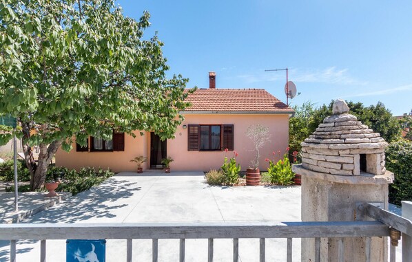 A house with a tiled roof, a stone fountain, and a potted plant in the foreground. - Lovely home in Sikici with WiFi (Sikici)