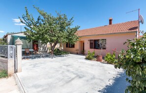 A single-story house with a tiled roof, a satellite dish, and a paved driveway. - Lovely home in Sikici with WiFi (Sikici)