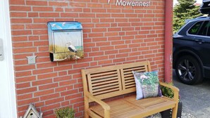 Un edificio in mattoni con una panchina di legno, una casetta per uccelli e un cartello con su scritto "Haus Mowennest".