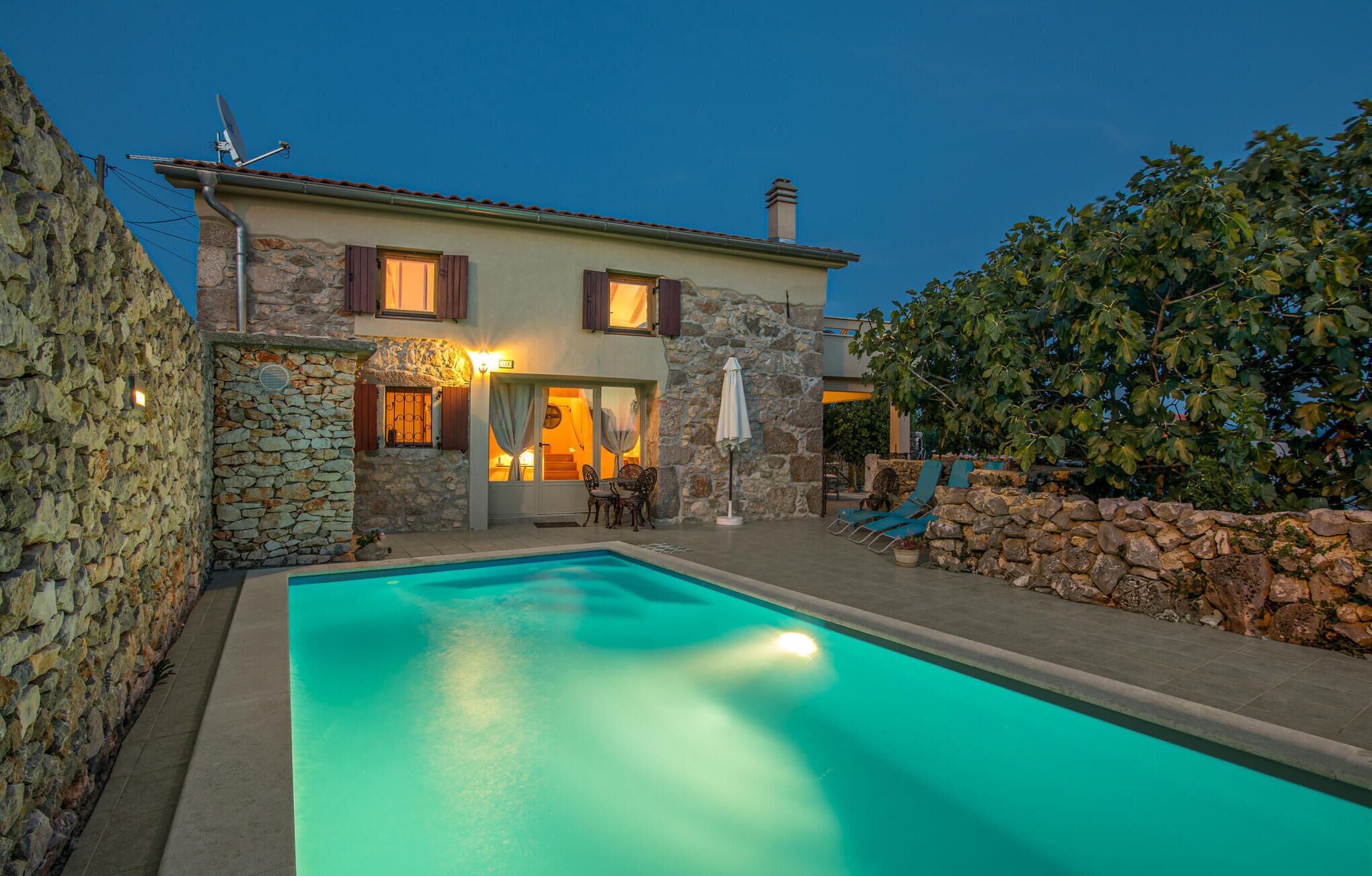 A two-story stone house with a swimming pool, stone walls, and outdoor seating.