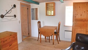 Een kamer met een houten tafel en stoelen, een kapstok, een spiegel en een zwarte lederen fauteuil.
