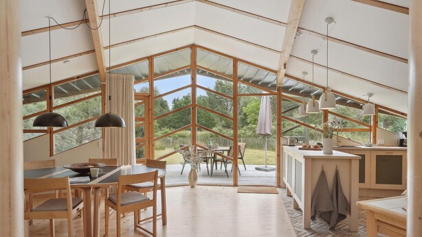 Une cuisine et une salle à manger spacieuses, aménagées en un seul espace ouvert, avec de grandes fenêtres, des poutres en bois et un plafond orné de motifs en chevrons.