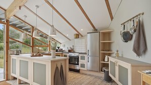 Une cuisine moderne avec des poutres en bois, un grand îlot central et un parquet disposé en motif à chevrons.