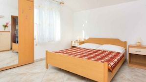 Een slaapkamer met een houten bed, een nachtkastje, een kaptafel, een kledingkast en een spiegel.