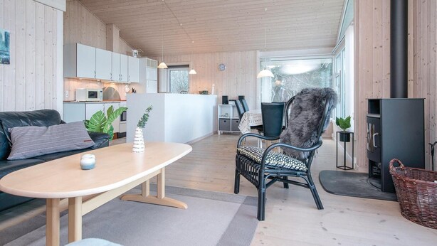 A modern living room with a sofa, a table, a chair, and a fireplace. - Gorgeous home in Løkken with sauna (Løkken)
