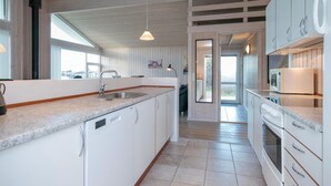A modern kitchen with white cabinetry, a granite countertop, and pendant lighting. - Gorgeous home in Løkken with sauna (Løkken)