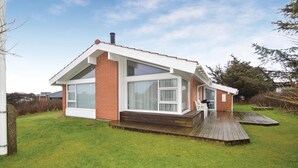 A modern house with a brick facade, large windows, and a wooden deck. - Gorgeous home in Løkken with sauna (Løkken)