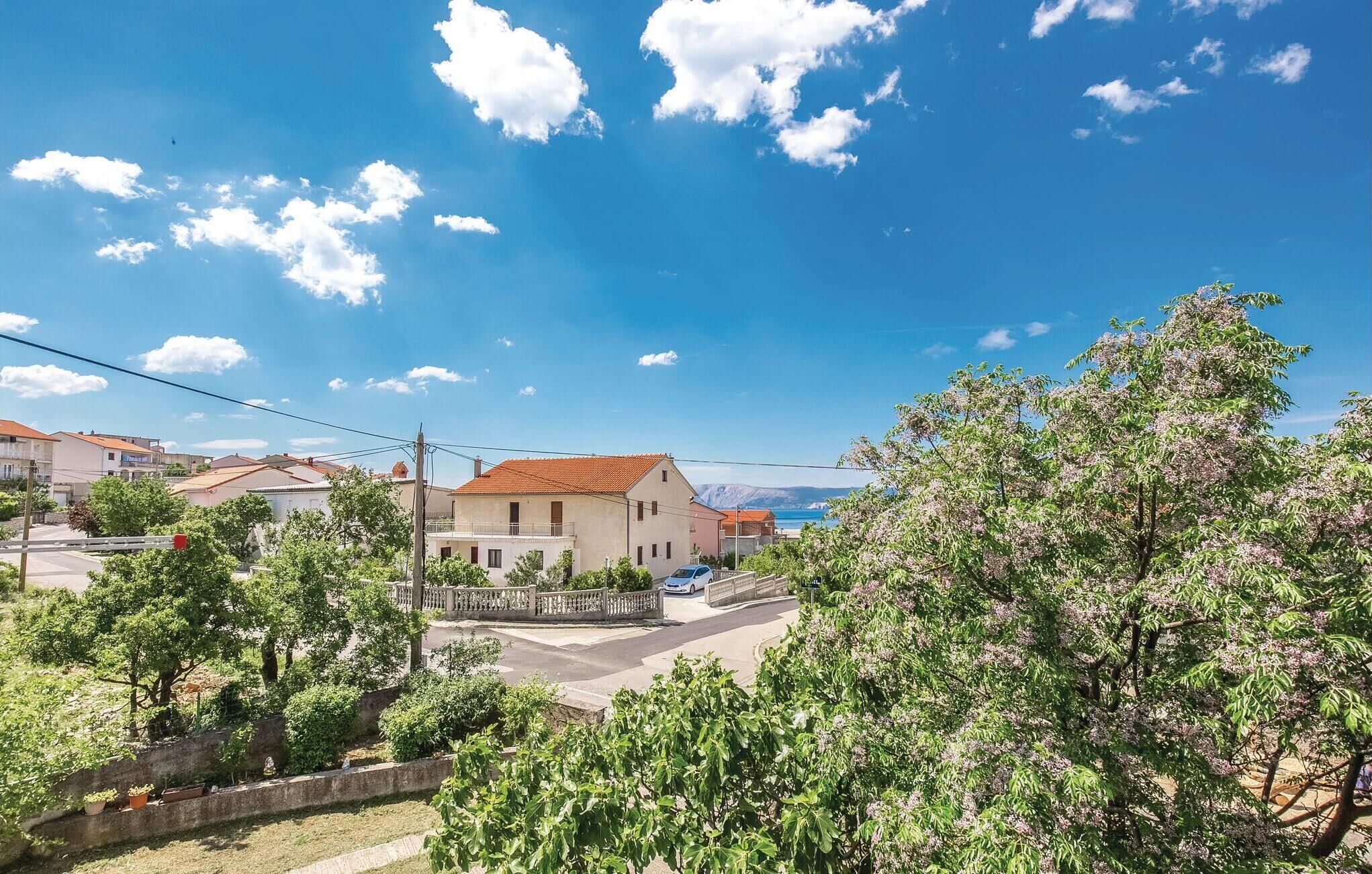 A residential area with houses, a clear sky, and a view of the sea.