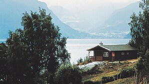 A cabin with a green roof, surrounded by trees and mountains, overlooking a body of water. - 2 bedroom beautiful home in Balestrand (Balestrand)