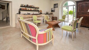 Un salon spacieux avec une table basse en bois, des fauteuils à rayures et une bibliothèque remplie de livres.
