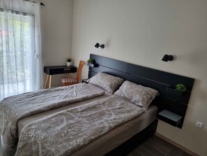 Een slaapkamer met een bed, nachtkastjes, een stoel en een bureau.