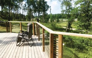 Un pontile in legno con una sedia a rotelle, con vista su una zona boschiva.