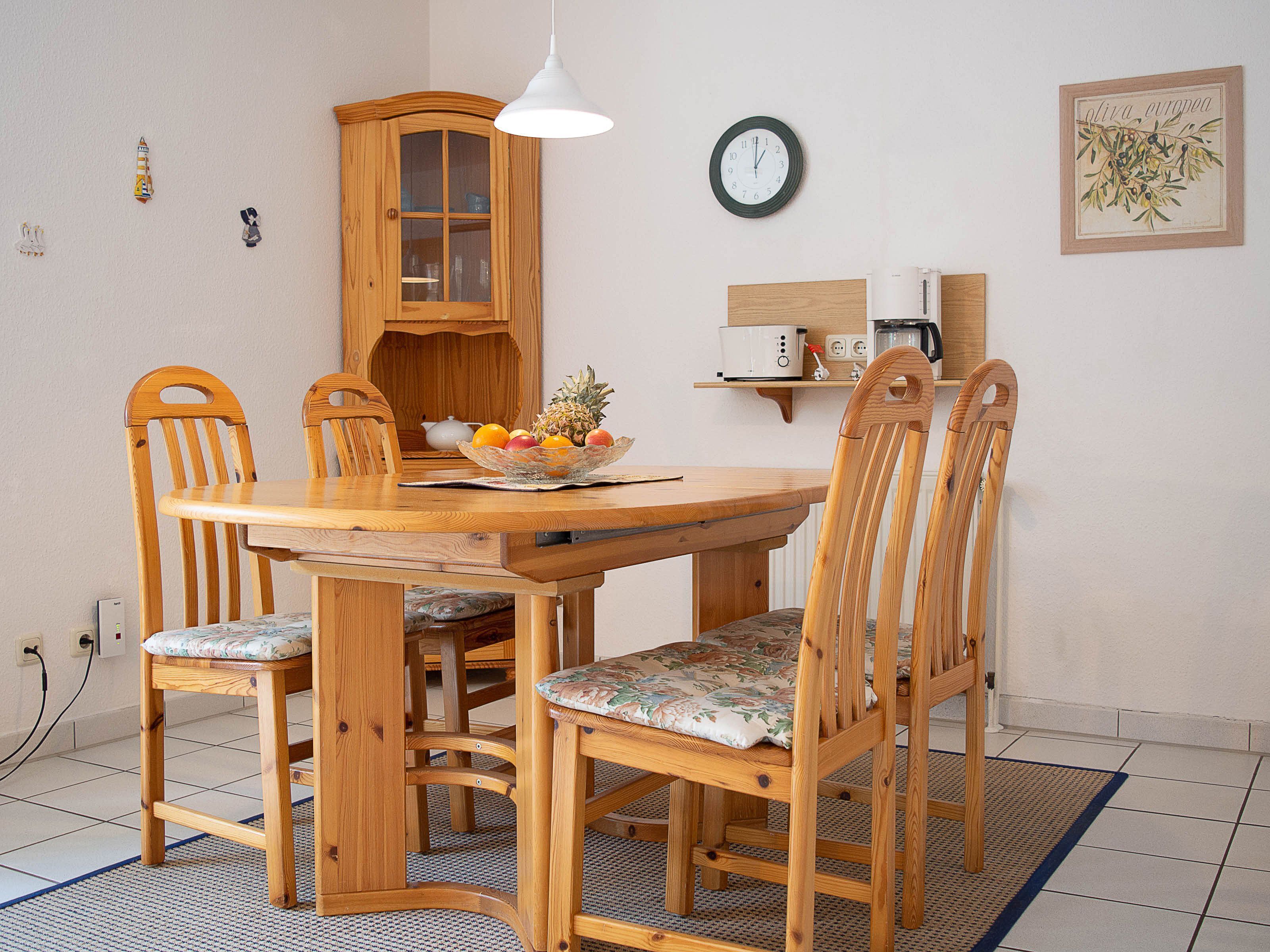 Ein Holzespeisesaal mit Stühlen, einer Obstschale, einer Uhr und einem Schrank.