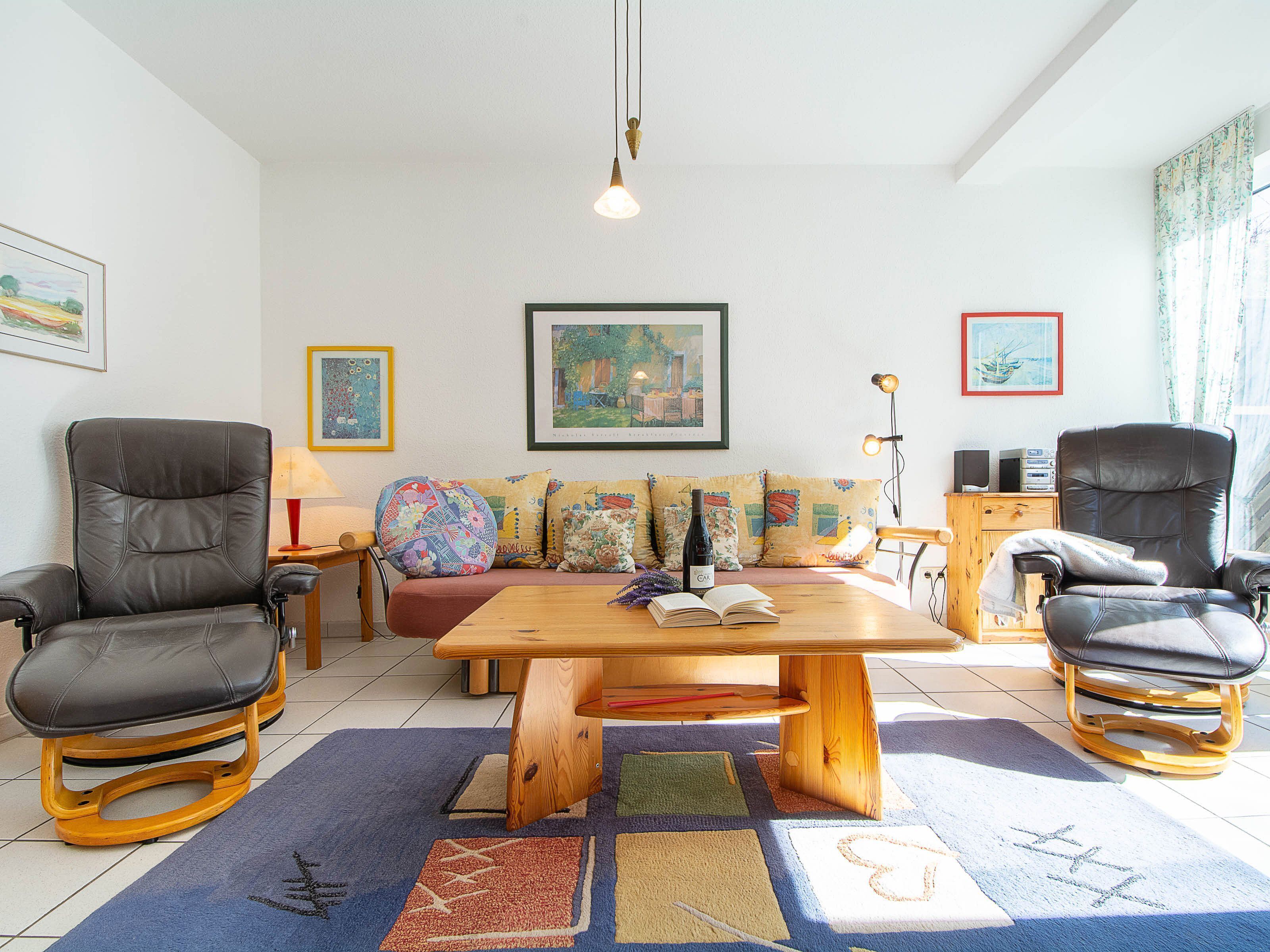 Uma sala de estar com sofá, duas poltronas, mesa de centro e tapete.