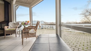 En balkon med fletstole, en bænk og udsigt over vandet.