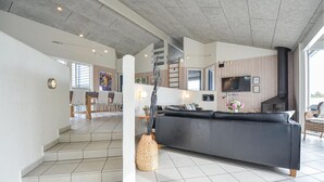 En moderne stue med sofa, pejs og spiseplads med stole og bord.