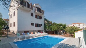 Un bâtiment à deux étages doté d’une piscine, d’un espace extérieur aménagé et surplombant un ciel dégagé.