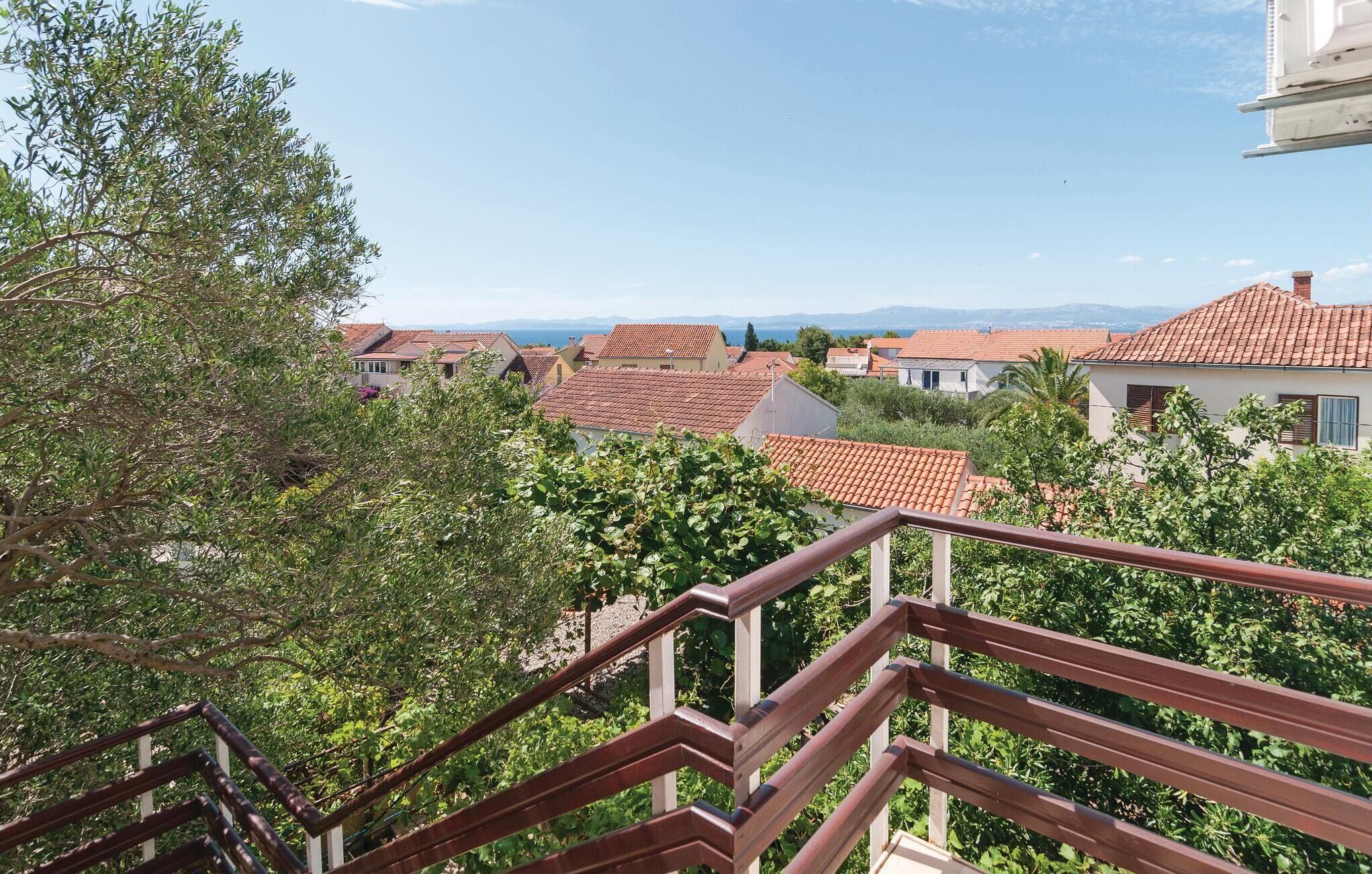 Zona residencial con tejados de tejas rojas, un balcón con baranda de madera y vistas despejadas de las casas y el paisaje circundante.