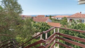 Un quartier résidentiel caractérisé par des toits recouverts de tuiles rouges, un balcon doté d’une balustrade en bois et offrant une vue dégagée sur les maisons et le paysage environnants.