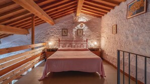 A cozy attic bedroom with a wooden ceiling, a bed with a pink bedspread, and two bedside lamps. - Gorgeous home in Pieve S. Stefano AR (Pieve S. Stefano AR)